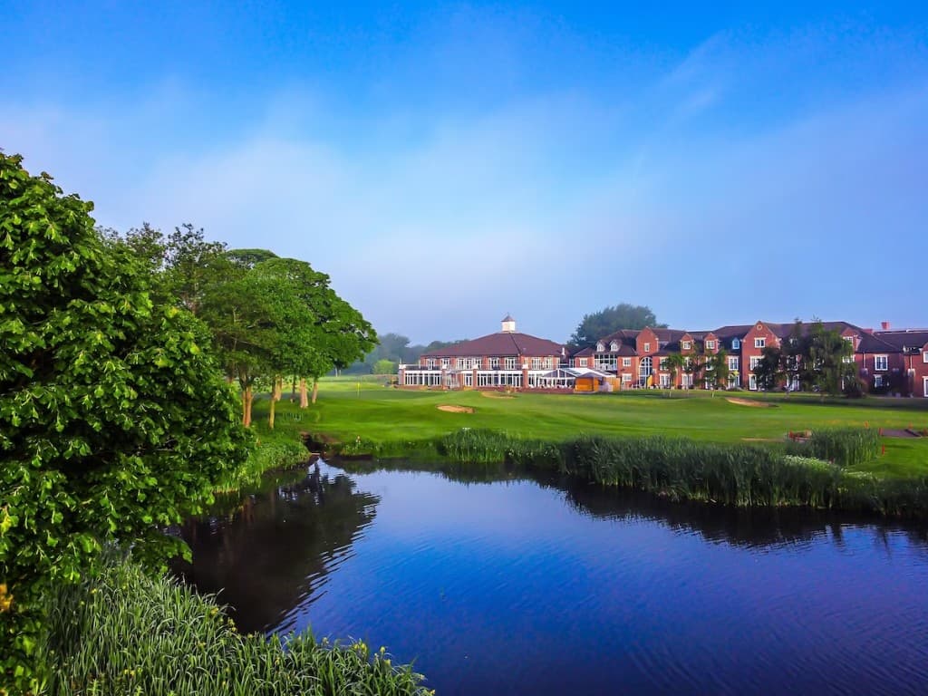 Golf hotel and fairway with lake reflection